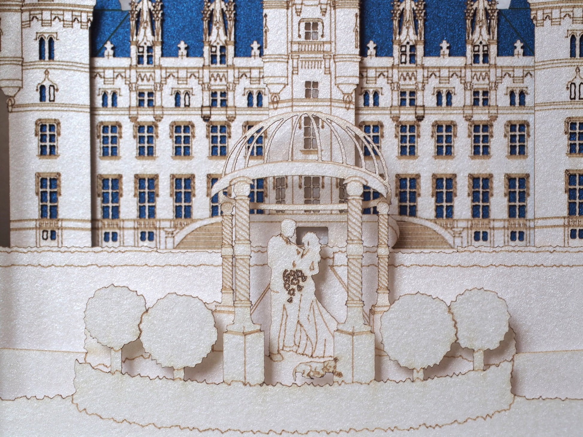Laser Cut couple paper figures in wedding arch and Castle Chateu de Challain behind